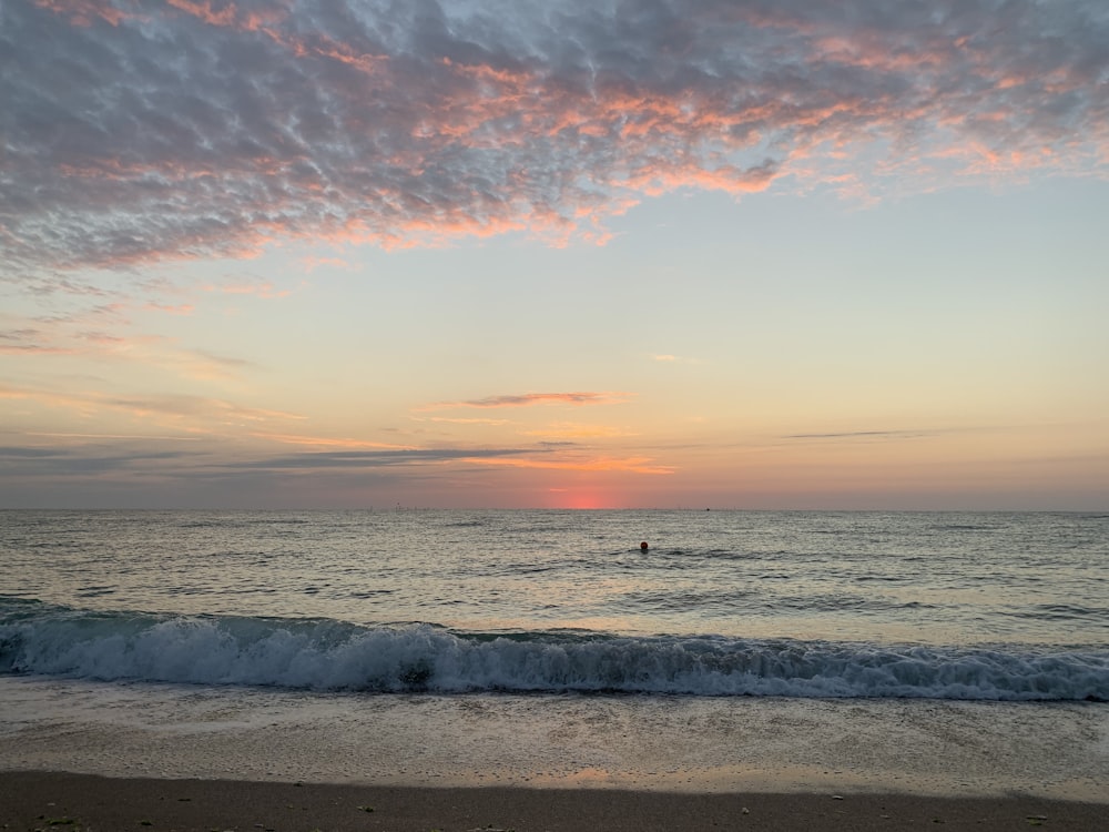 sea waves crashing on shore during sunset