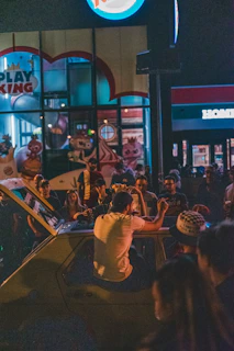 A vibrant group of college students enjoying late-night burgers and fries at The College Grill, with campus lights glowing in the background.