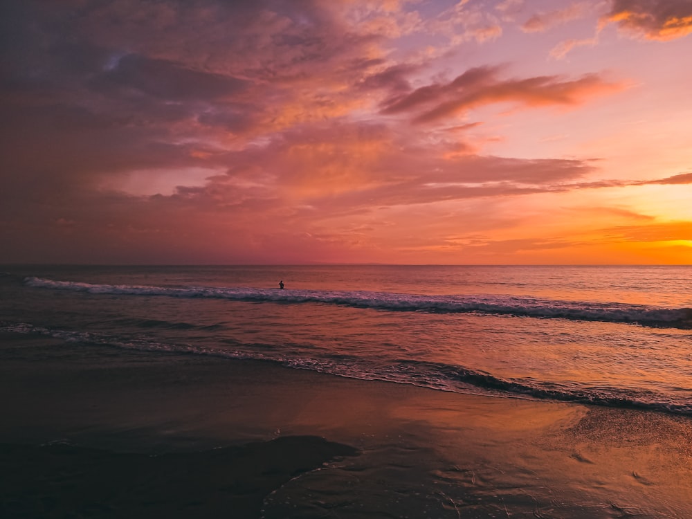 ocean waves crashing on shore during sunset