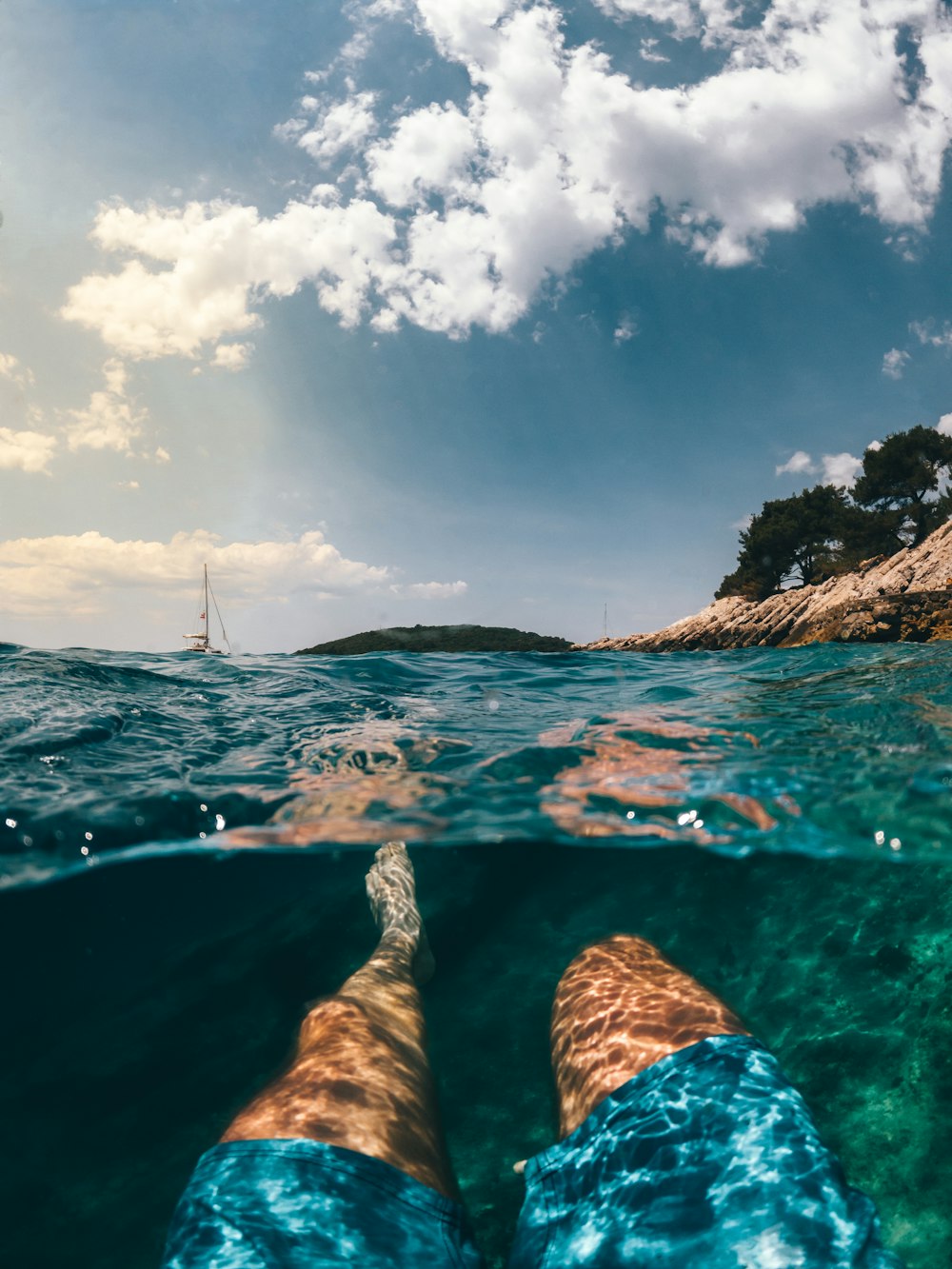 person in water under blue sky and white clouds during daytime