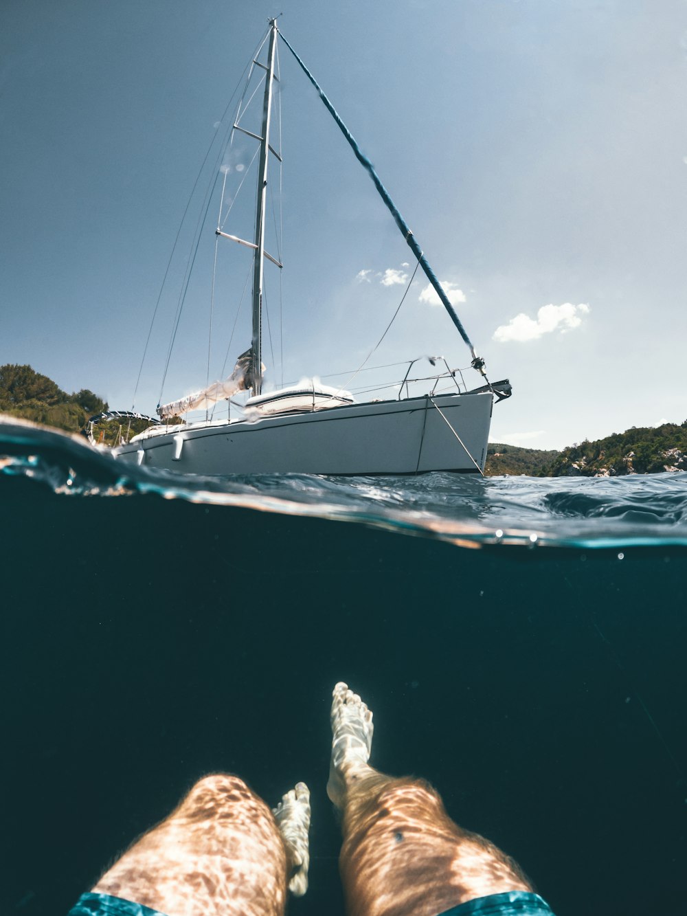 person in white and blue sailboat on sea during daytime