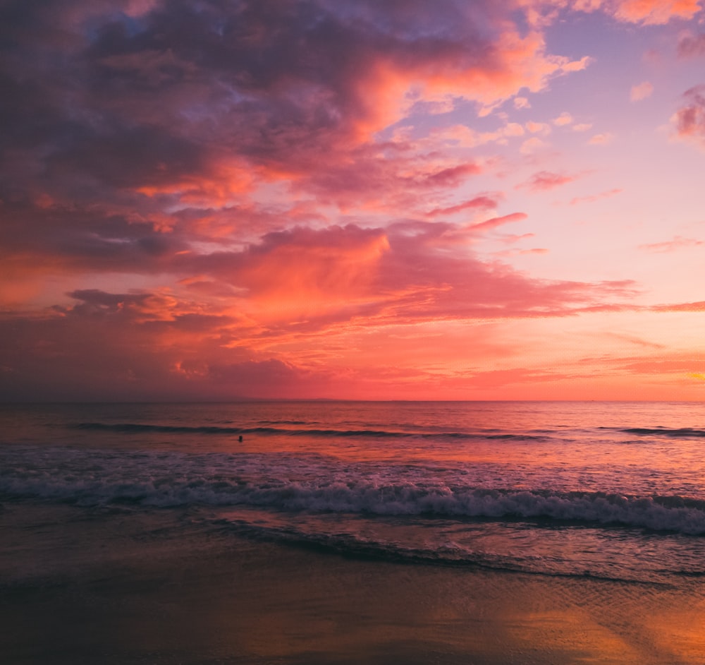 sea waves crashing on shore during sunset