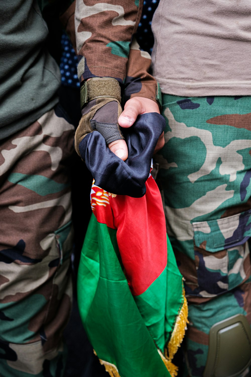 person in camouflage jacket holding red textile