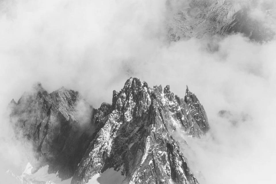 Majestic mountain range with snow-capped peaks shrouded in dense fog and cloud cover