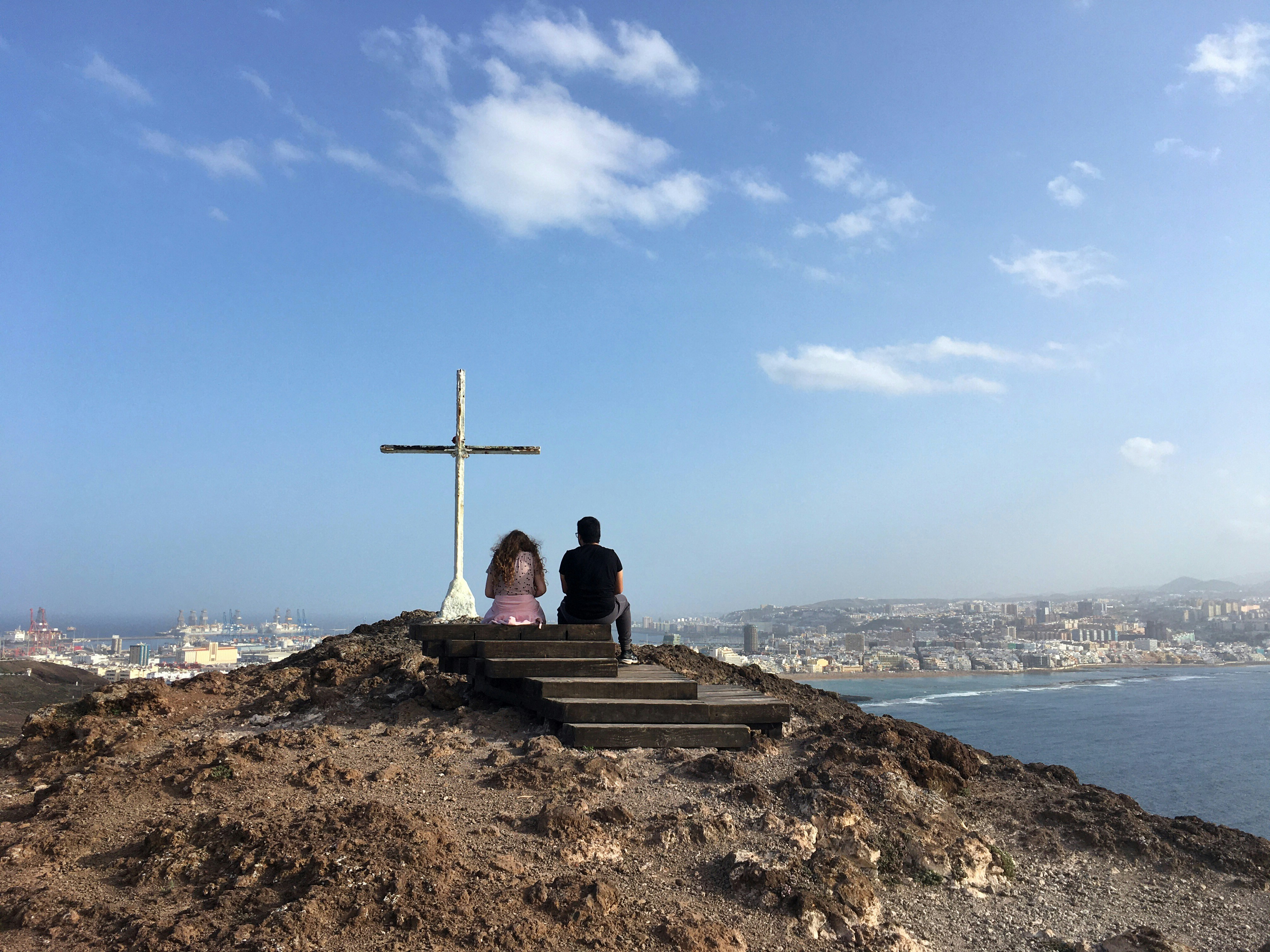 man sitting on brown rock near body of water during daytime