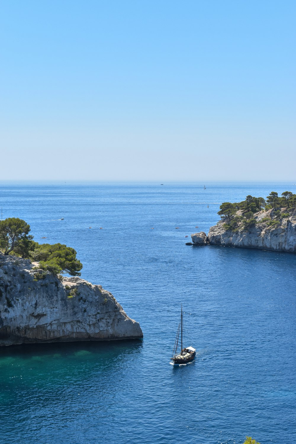 formazione rocciosa verde e marrone accanto al mare blu sotto il cielo blu durante il giorno