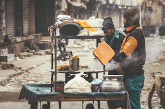 Close-up of hands preparing traditional street food with fresh ingredients in a bustling city kitchen.