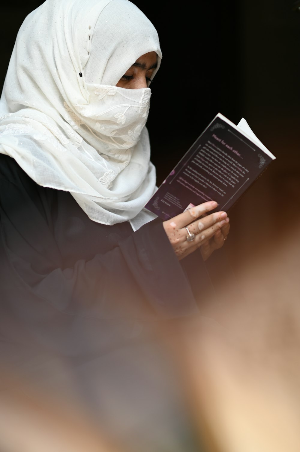 person in white hijab holding book