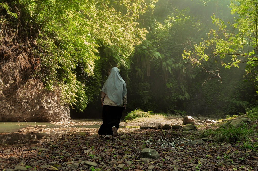 woman in white long sleeve shirt and black skirt walking on forest during daytime