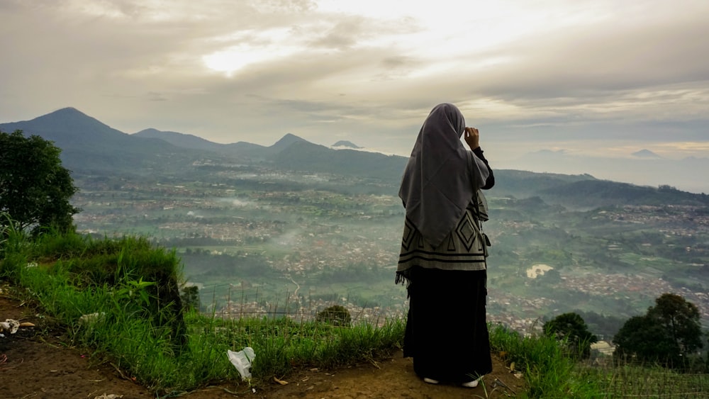 woman in black and white hijab standing on green grass field during daytime