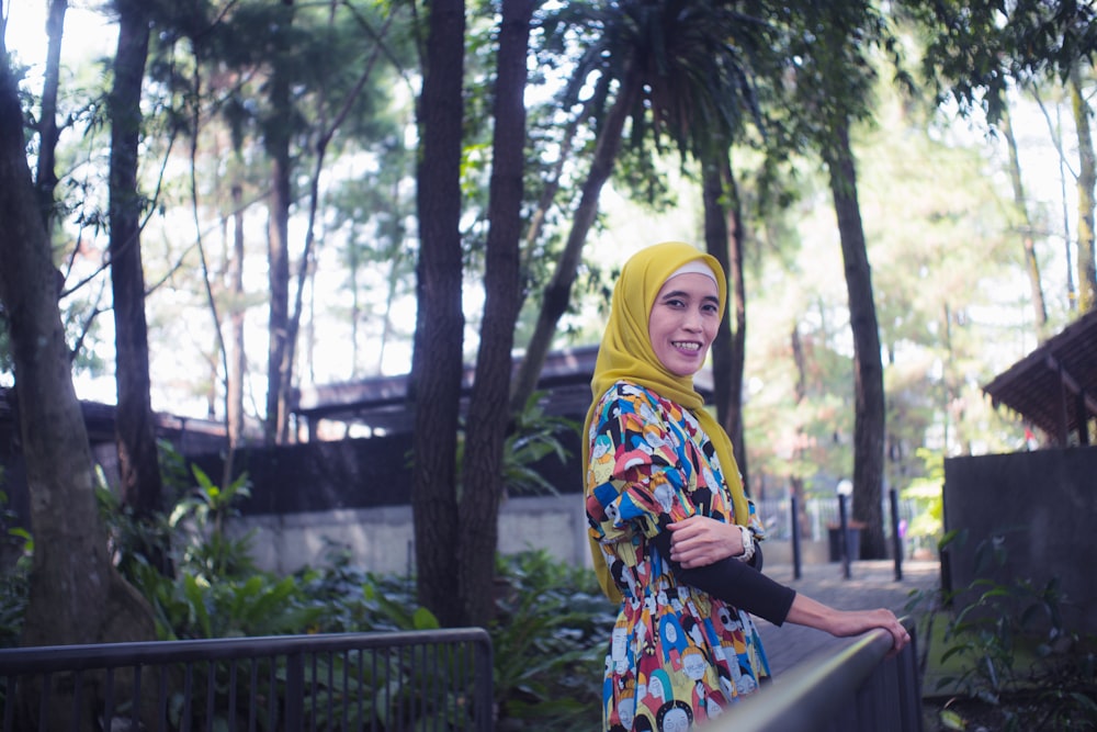 woman in yellow hijab standing near green trees during daytime