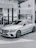 A happy customer standing next to their new Mercedes-Benz, smiling with the gleamdrive dealership in the background.