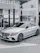 A happy customer standing next to their new Mercedes-Benz, smiling with the gleamdrive dealership in the background.