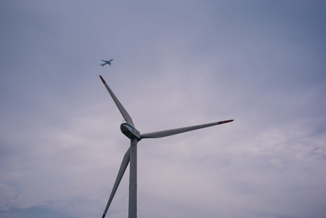 white wind turbine under gray sky