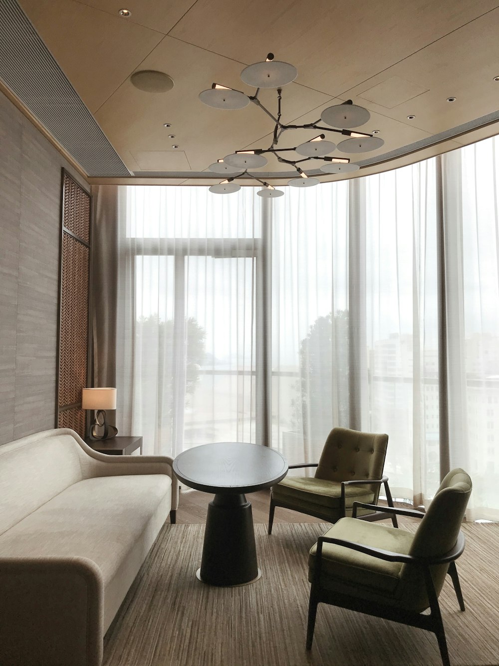 black and gray office rolling chair beside white window curtain