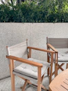 Outdoor patio with wooden chairs and a small table surrounded by greenery.
