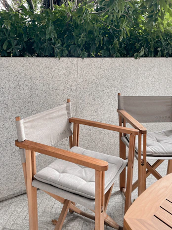 Close-up of a handcrafted wooden Vertexa chair with soft cushions on a stone terrace.