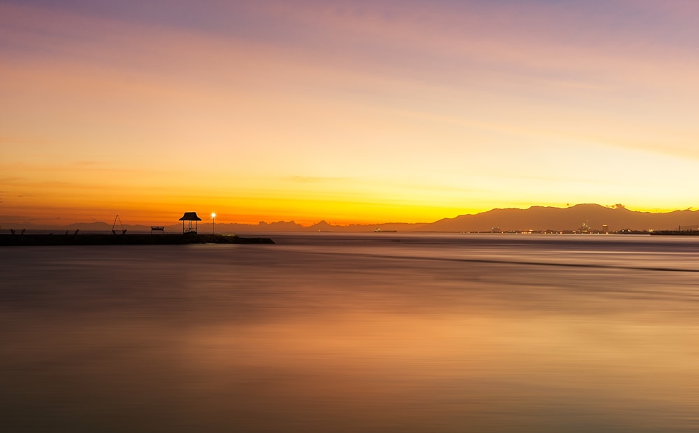 silhouette of boat on sea during sunset