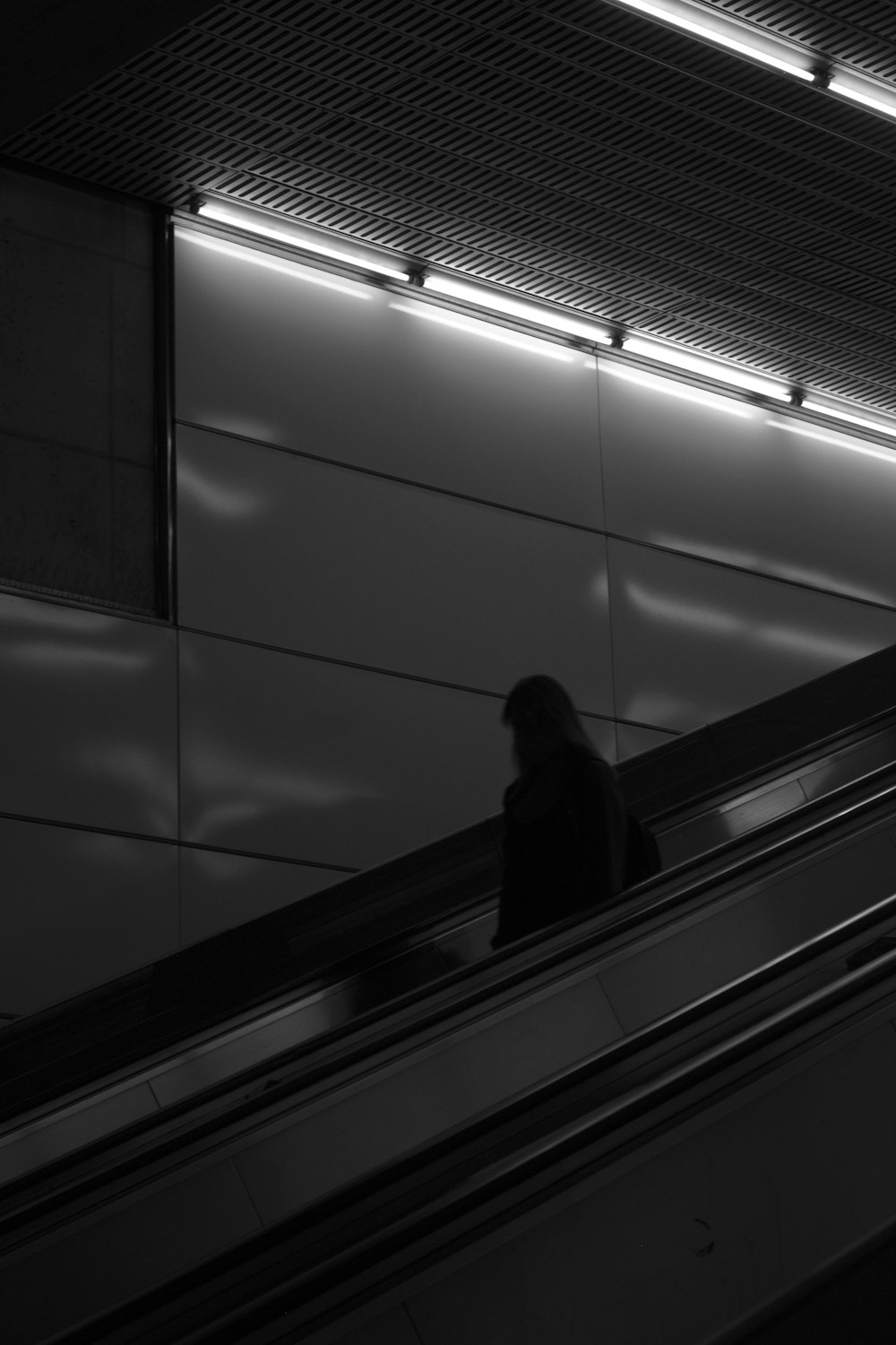person in black coat standing on escalator