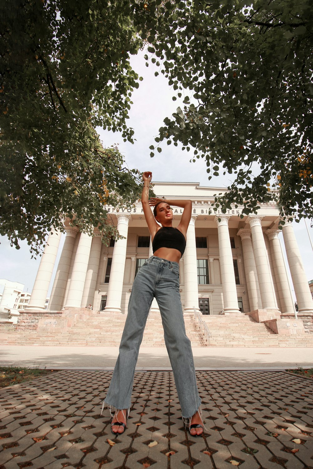 woman in black t-shirt and gray denim jeans standing on brown concrete floor during daytime