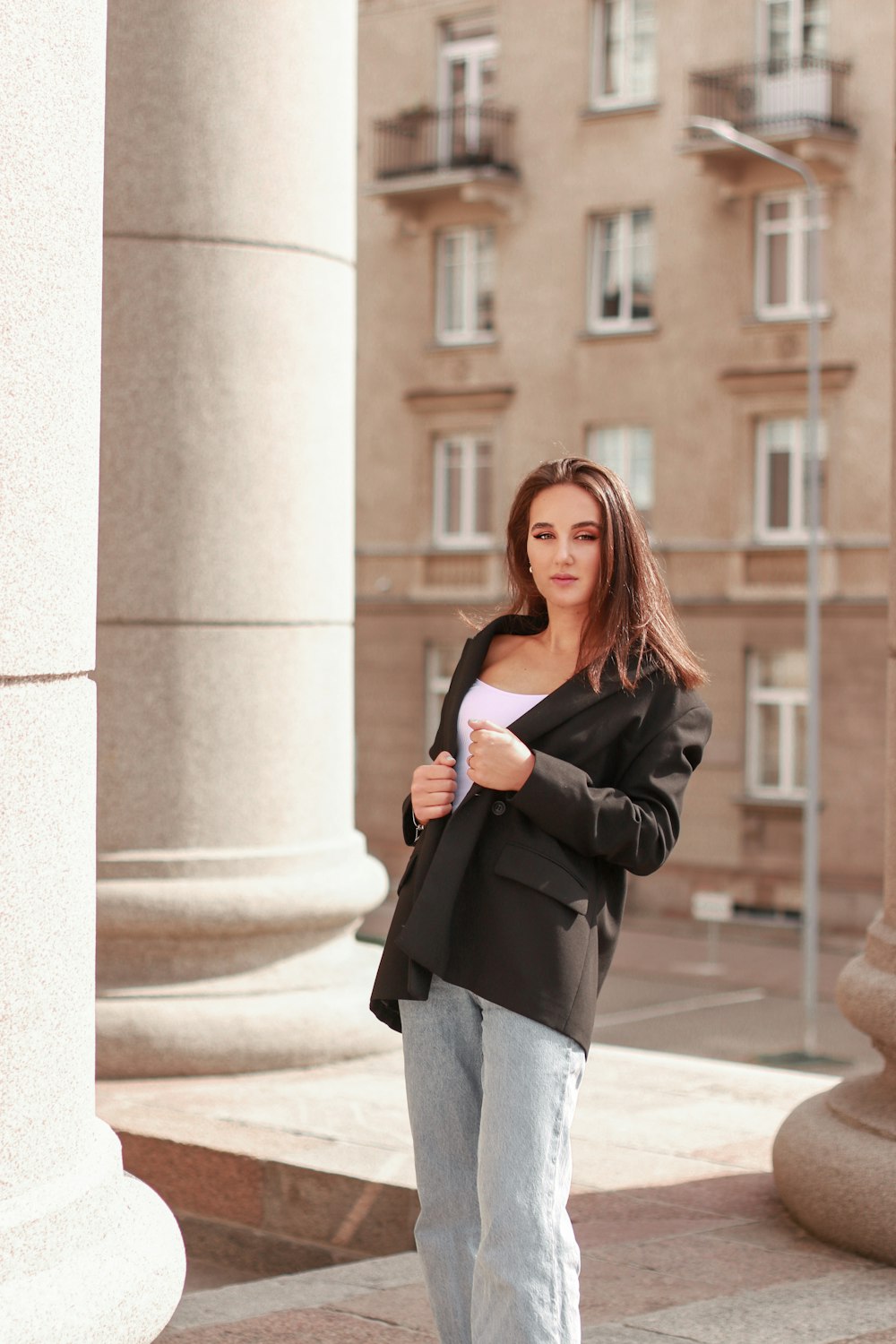 woman in black leather jacket and gray pants standing on gray concrete floor during daytime