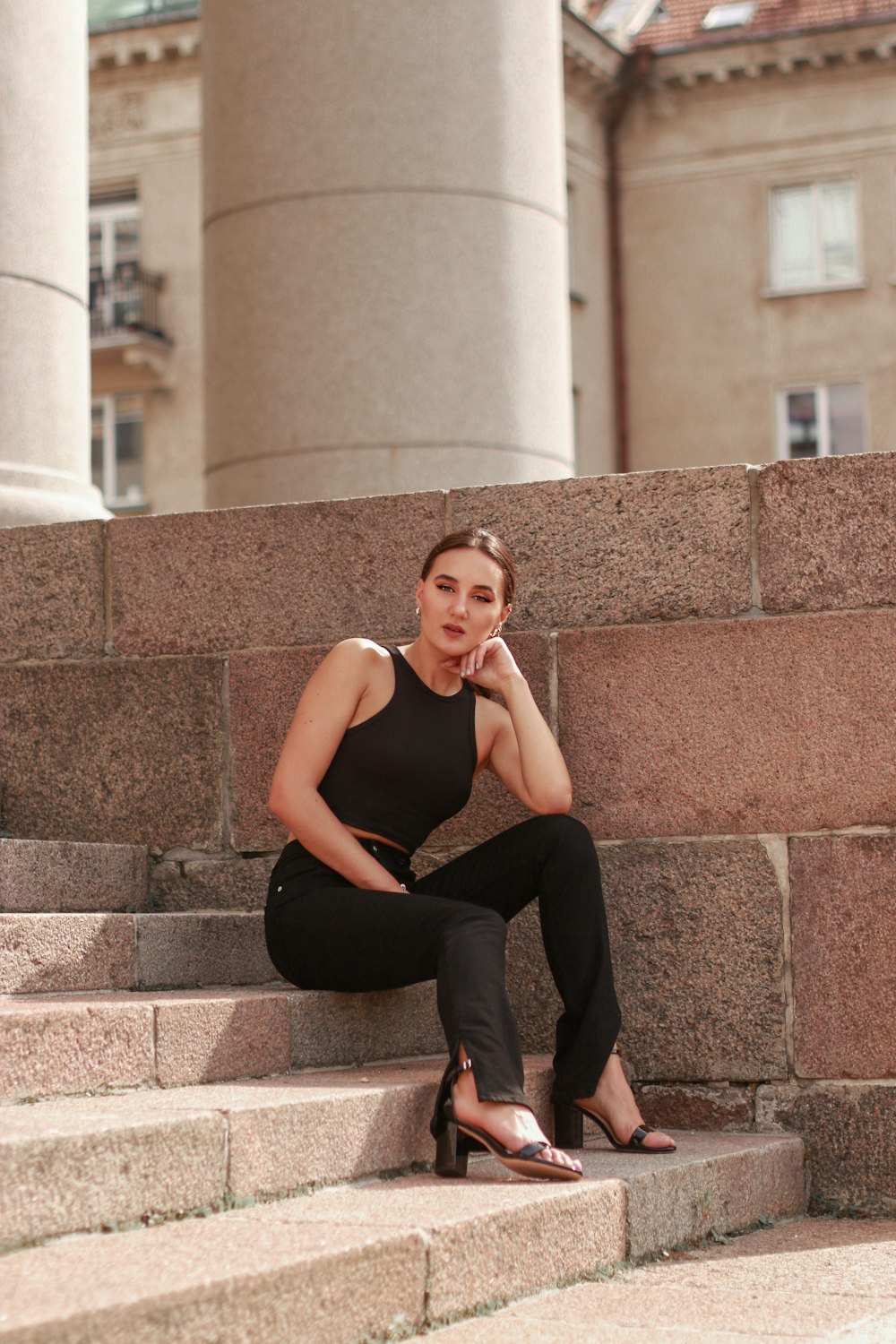 woman in black tank top and black pants sitting on concrete stairs