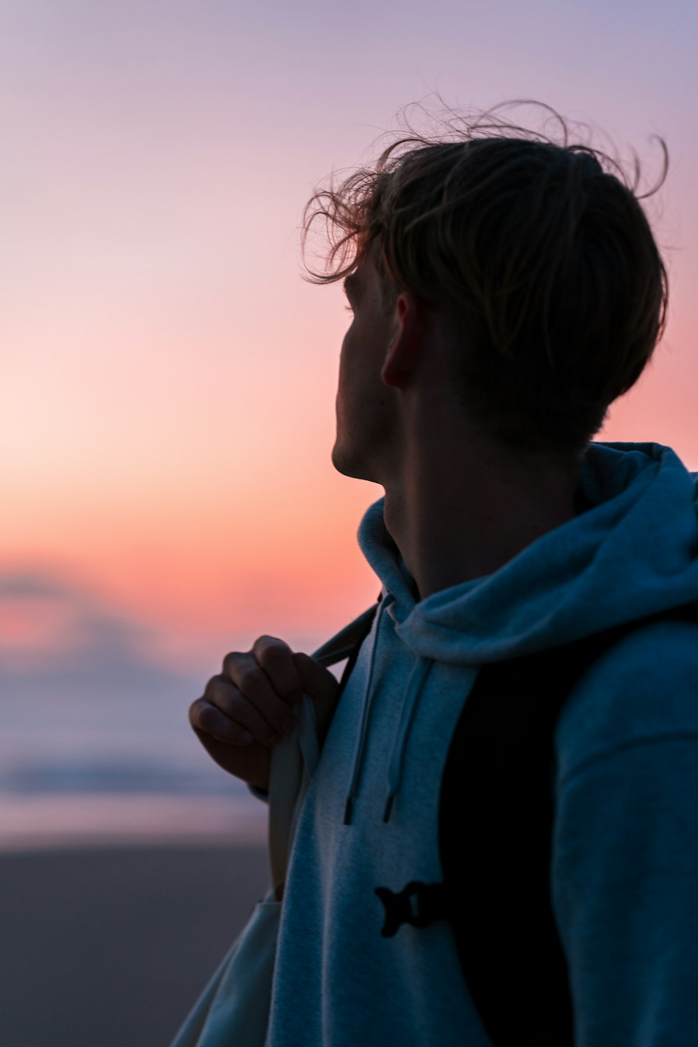 man in blue hoodie looking at the sea during daytime