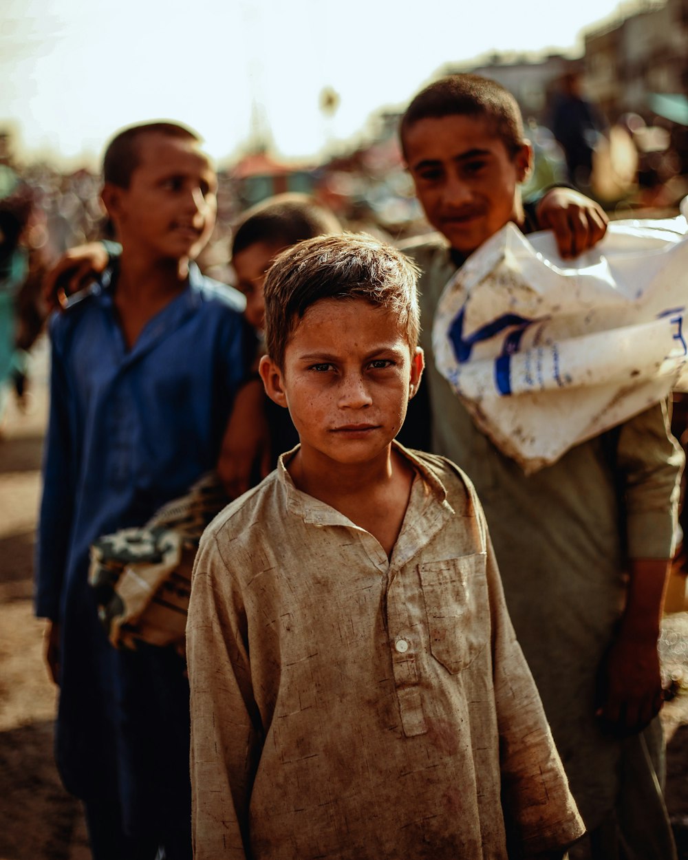 boy in brown button up shirt standing near people during daytime