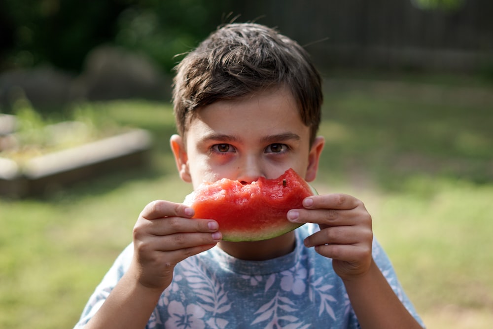 Junge im blau-weißen Rundhalsshirt isst Wassermelone