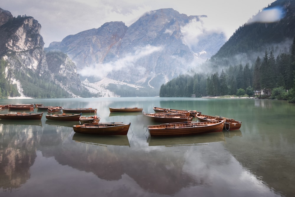 brown boat on calm water near snow covered mountain during daytime
