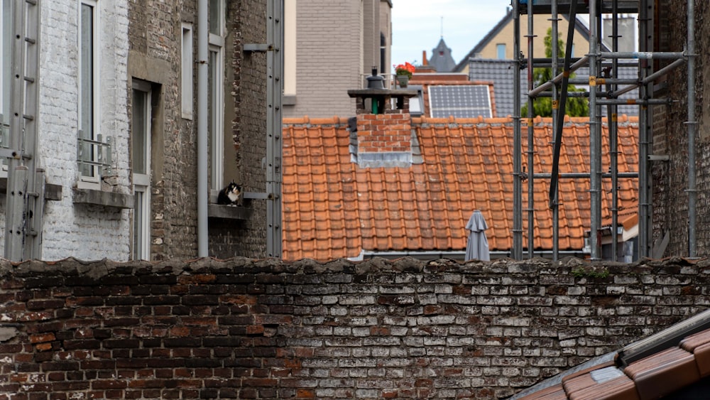 parede de tijolo marrom perto do edifício de concreto cinza durante o dia