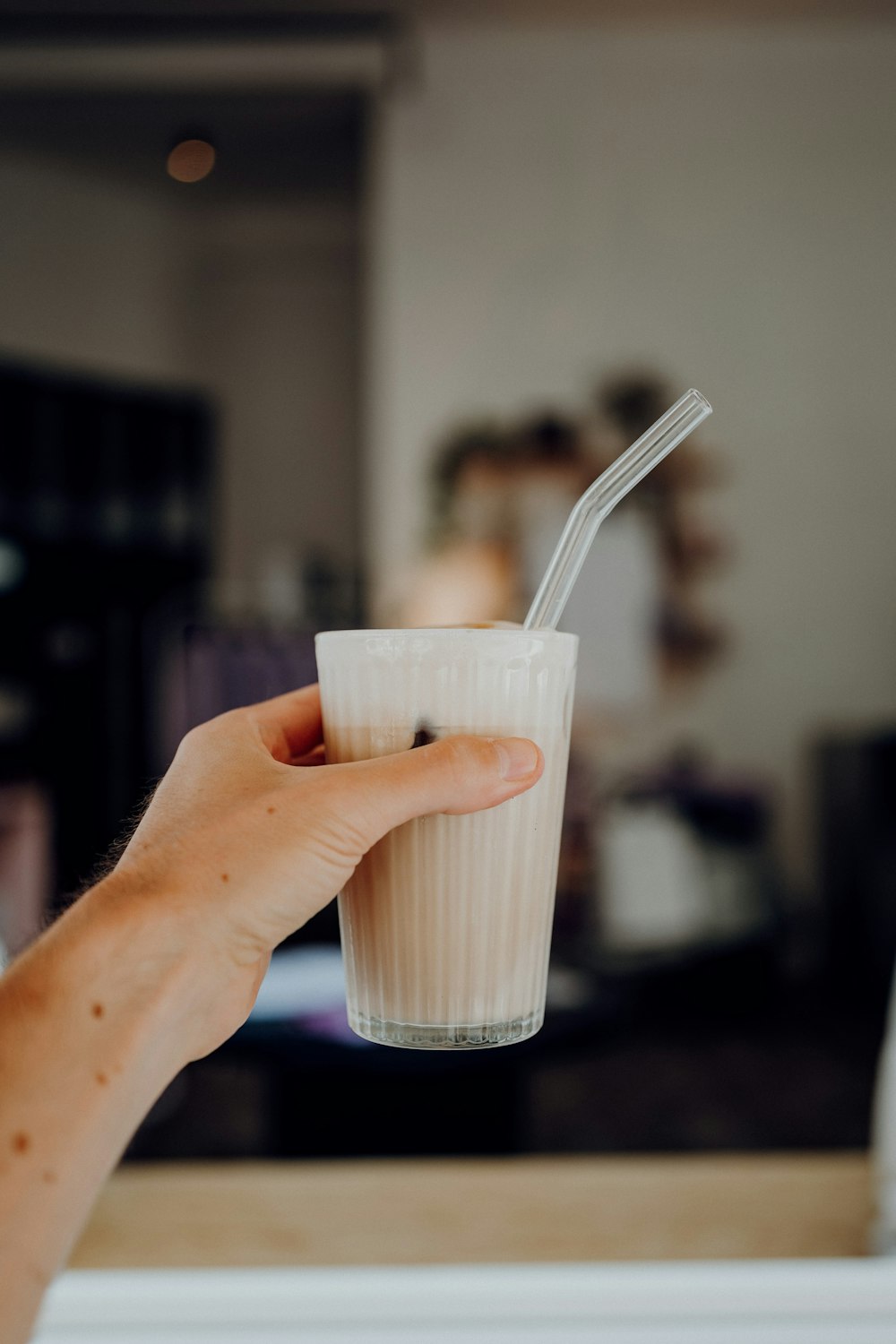 person holding white plastic cup with white plastic spoon