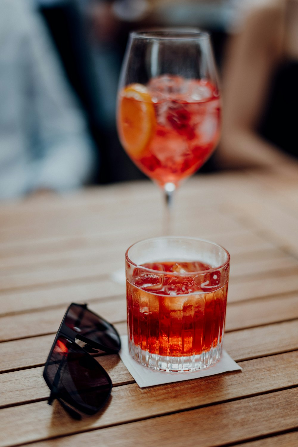 clear drinking glass with red liquid on brown wooden table