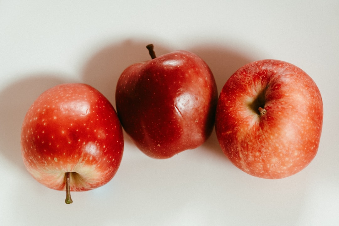 3 red apples on white surface