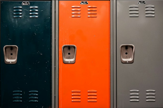 A long school hallway lined with blue lockers, representing the inside of a public school building