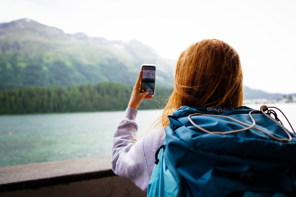 woman in gray jacket holding smartphone