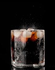 clear drinking glass with ice and black liquid