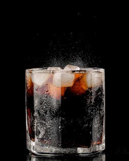 clear drinking glass with ice and black liquid