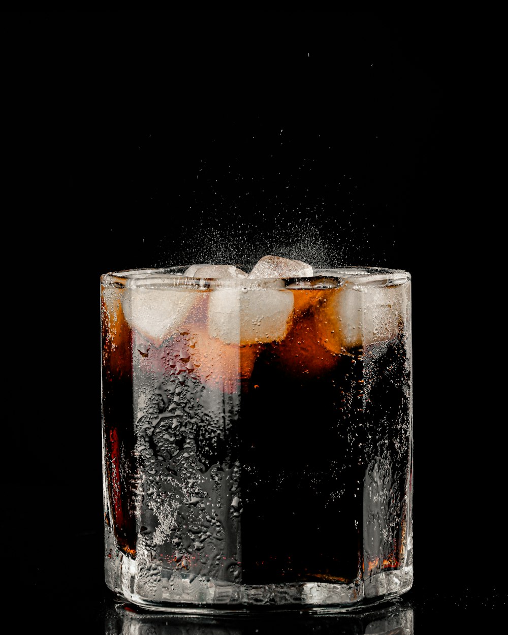 clear drinking glass with ice and black liquid