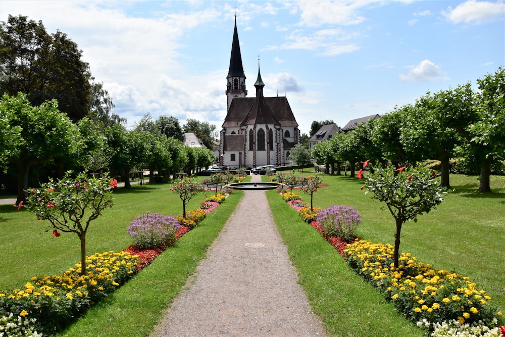 gray concrete church near green trees under white clouds during daytime