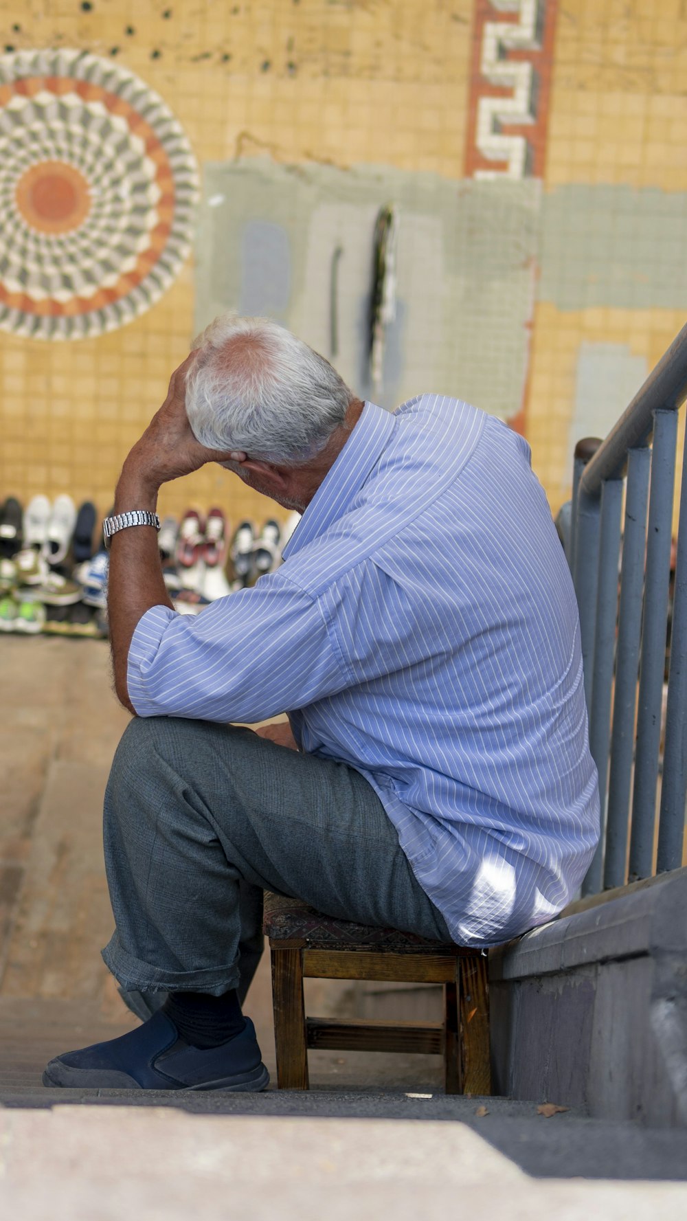 man in blue and white pinstripe dress shirt and gray pants sitting on brown wooden bench