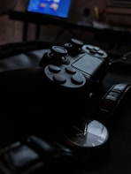 Close-up of a colorful handmade jewelry piece next to a sleek futuristic gaming controller on a wooden desk.