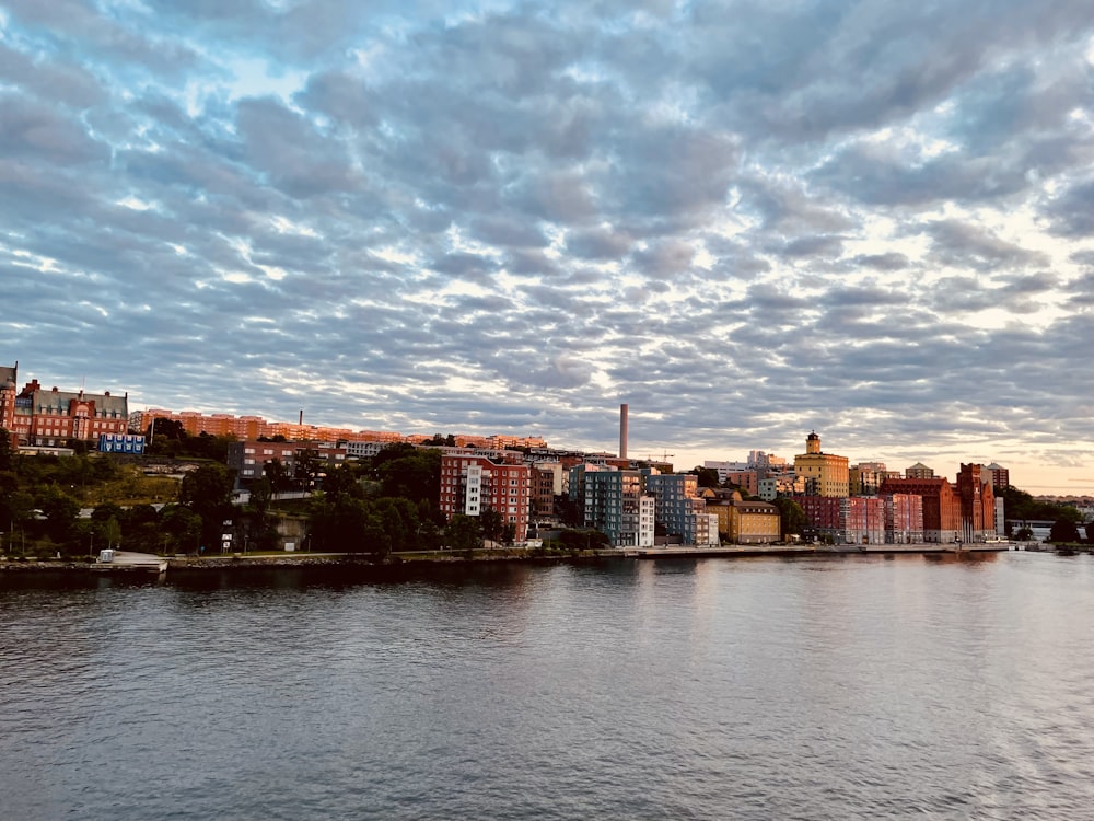 city skyline near body of water under cloudy sky during daytime