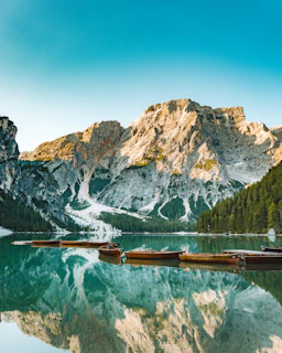 Colorful boats gently bobbing on the crystal-clear waters of Lake Reschen under a blue sky