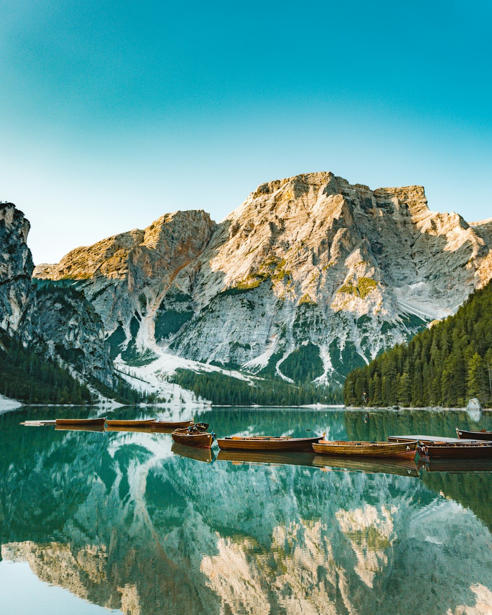 brown wooden dock on lake near mountain range