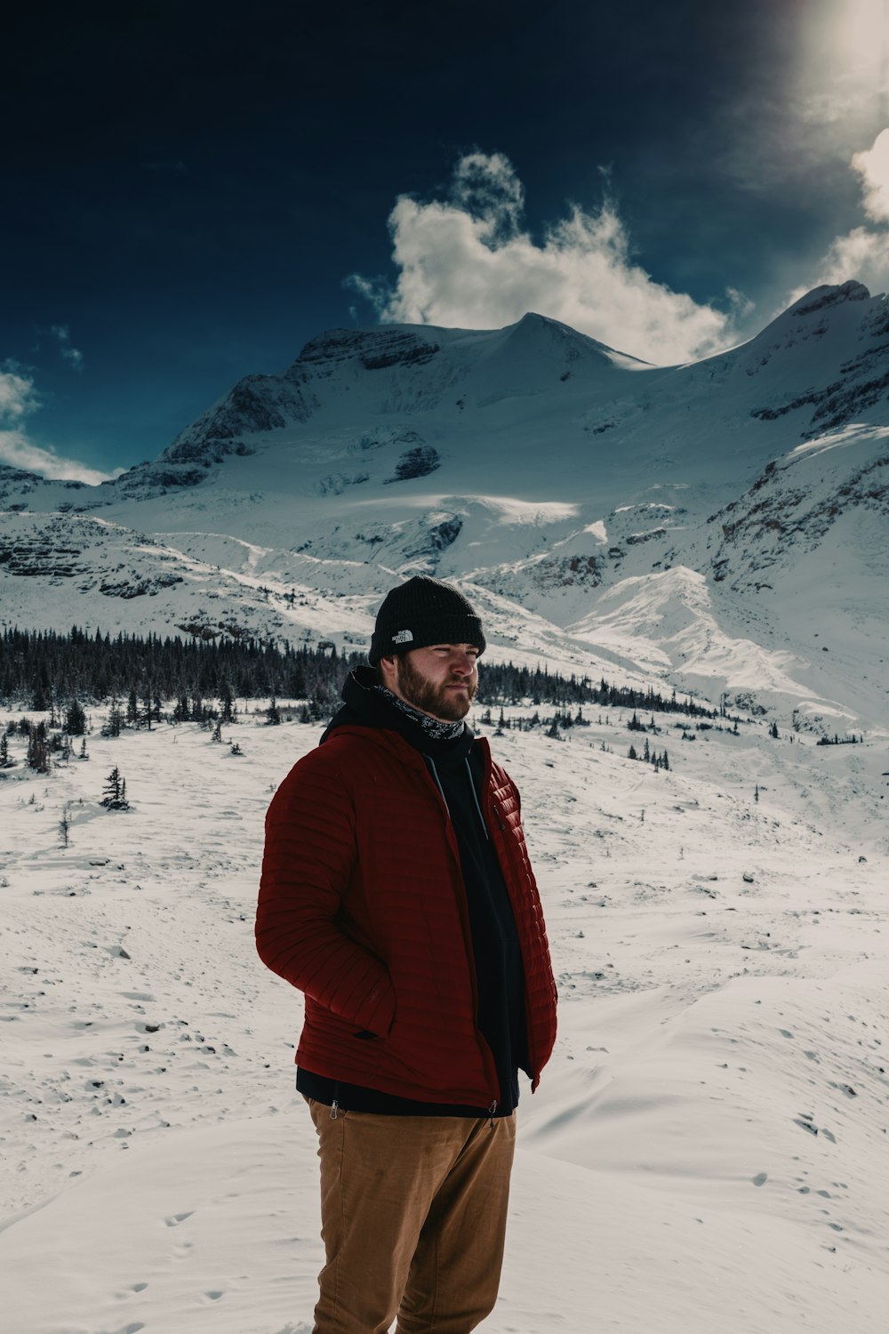 man in red jacket standing on snow covered ground