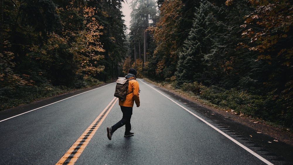 man in brown jacket and black pants walking on the road