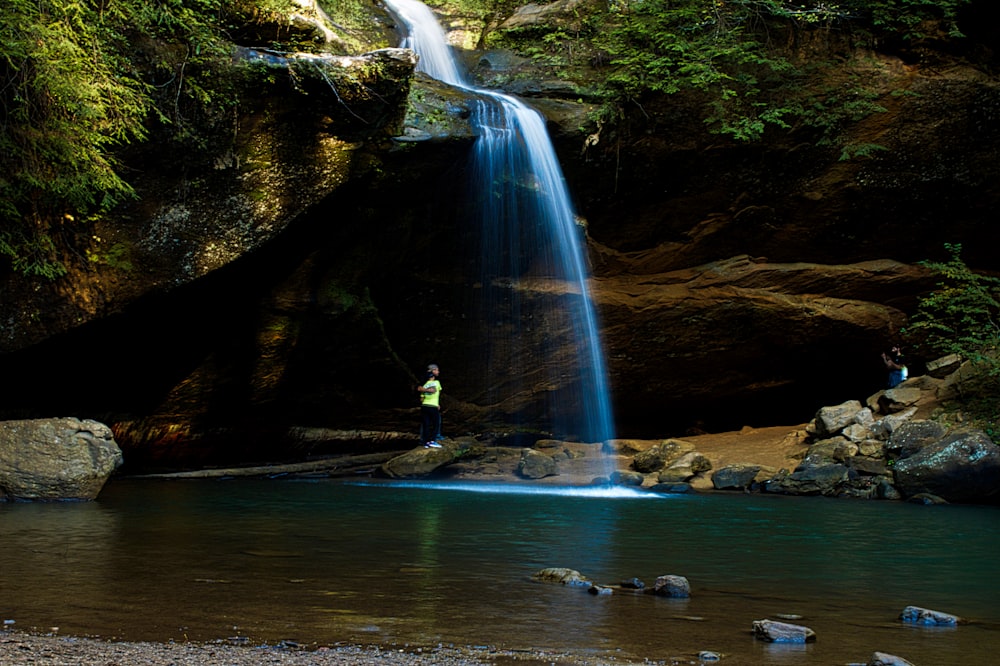 people swimming on water falls during daytime