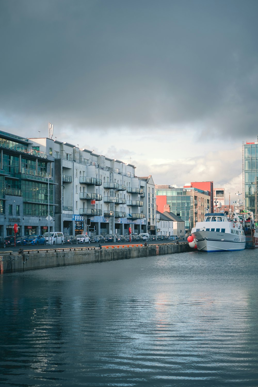 Bateau blanc sur l’eau près d’un bâtiment en béton pendant la journée