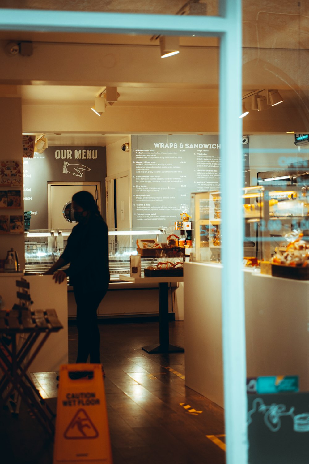 man in black jacket standing in front of food counter